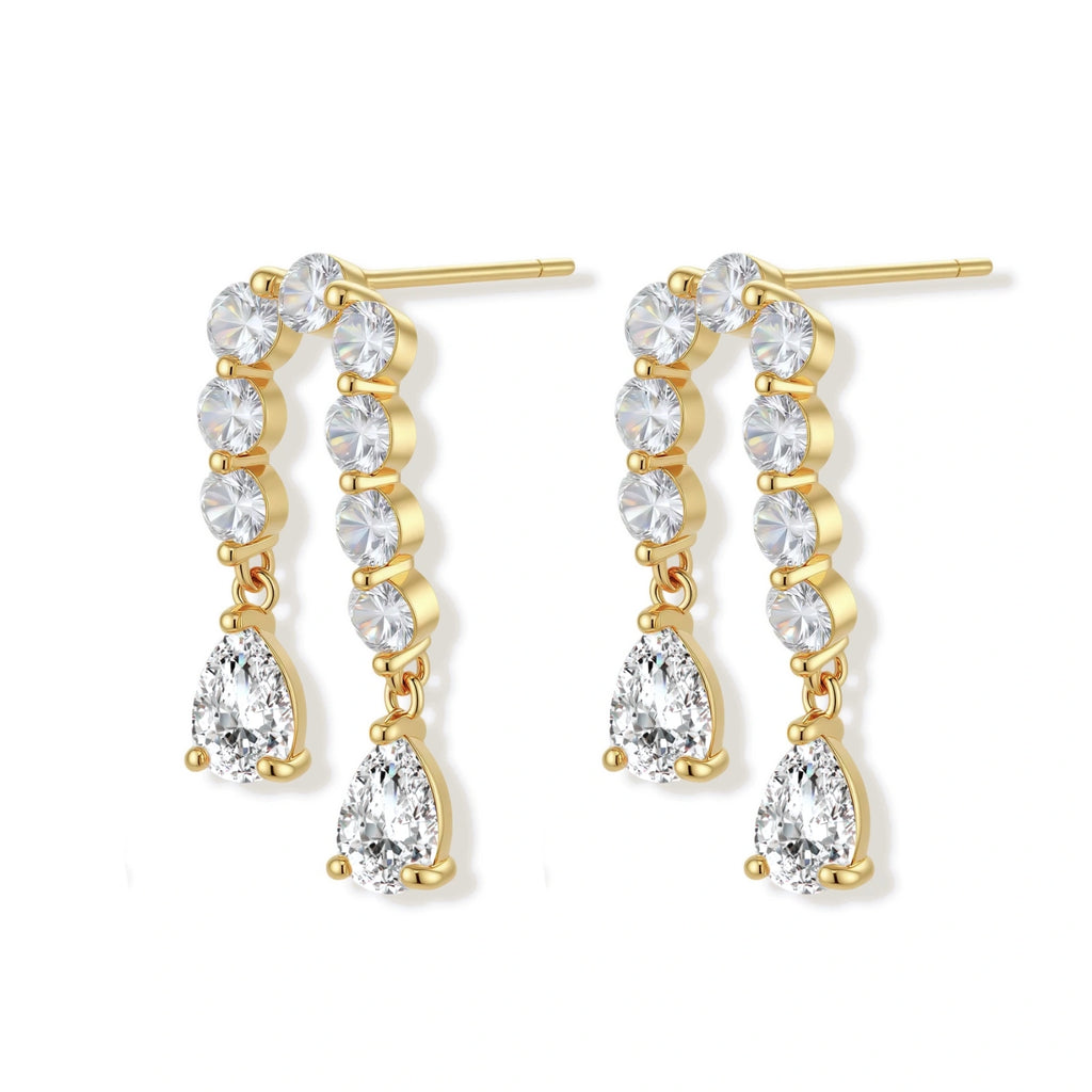 Gold-plated earrings with vertical line of clear crystals and teardrop pendants on neutral background