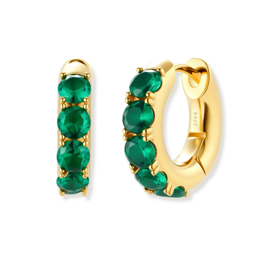 Close-up of gold-plated huggie hoop earrings featuring four emerald green cubic zirconia stones on white background.