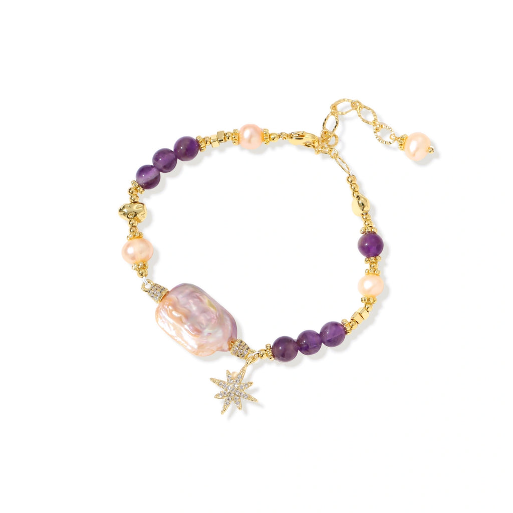 Gold-plated bracelet with baroque pearl centerpiece, amethyst beads, and crystal star charm on white background.