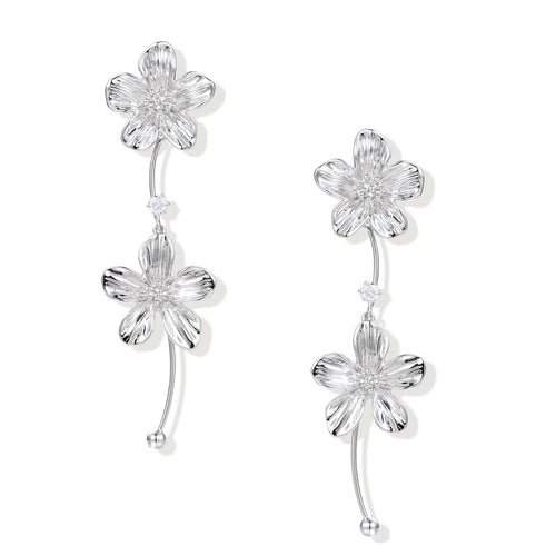 Silver-white asymmetric earrings with textured flower petals and crystal centers on cream background