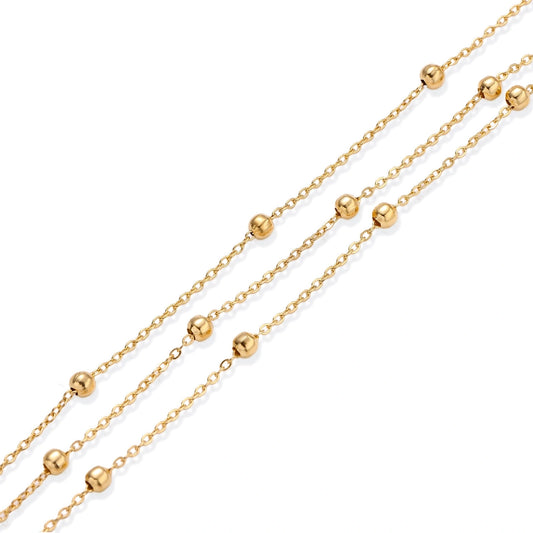 Three-strand gold-plated bracelet with clustered ball beads and adjustable clasp on cream background