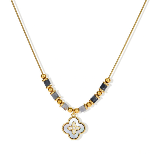 Gold-toned beaded necklace with grey stones and quatrefoil abalone shell pendant on cream background.