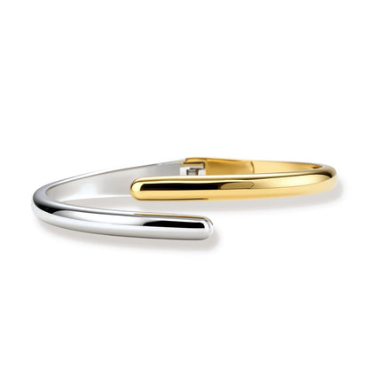 Polished two-tone bypass cuff bracelet in 18K gold plated and silver stainless steel with overlapping tapered ends.