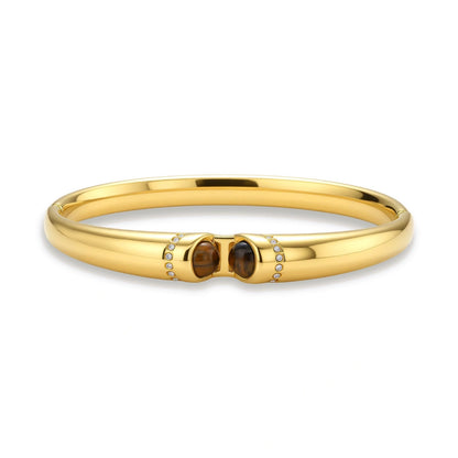 Polished gold bangle with two oval tiger's eye cabochons flanked by pavé diamond accents at center clasp.