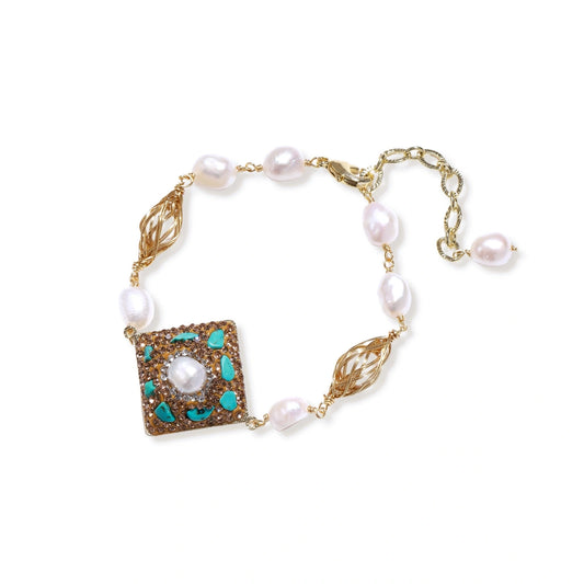 Gold-plated bracelet with baroque centerpiece, turquoise stones, freshwater pearls, and ornate chain links on cream background.