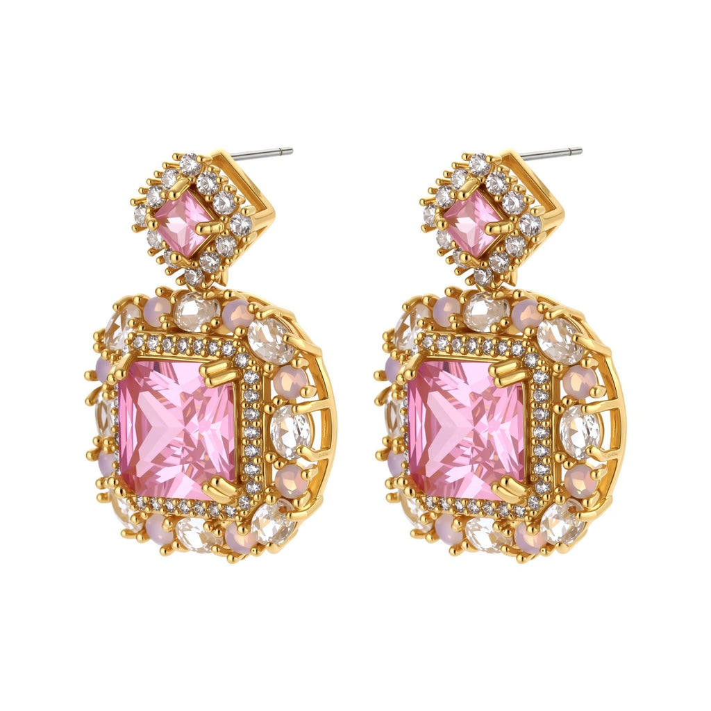Ornate gold-plated jewelry set with rose pink zirconia center stones and crystal accents on cream background.