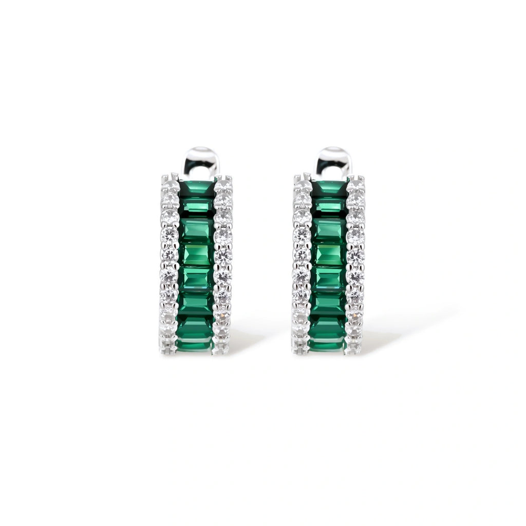 White gold plated jewelry set with emerald green rectangular stones and clear crystals in geometric rows on white background.