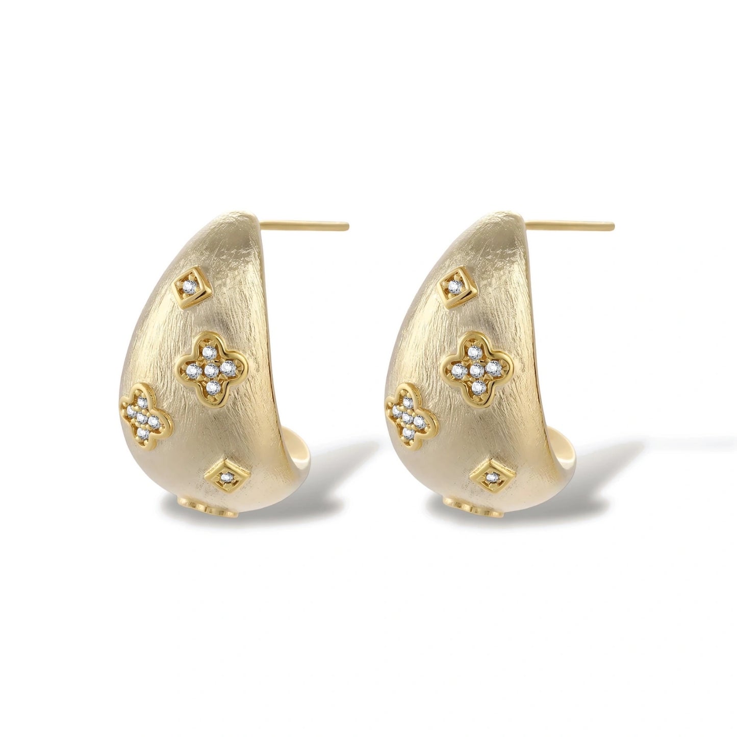 Curved gold-plated hoop earrings with four-leaf clover and diamond-shaped crystal details on white background