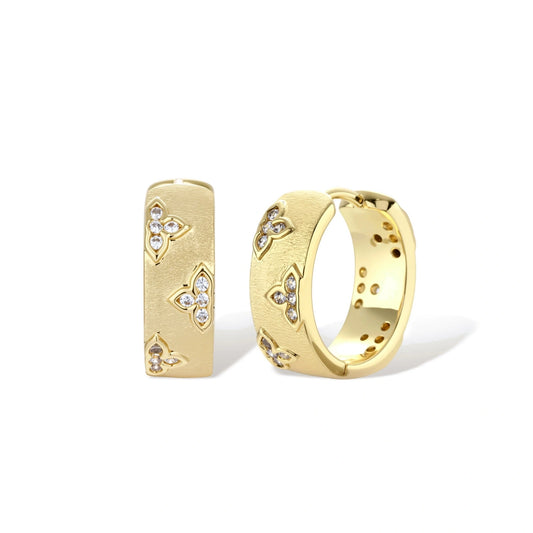 Gold-plated hoop earrings with textured surface and raised floral motifs set with clear zirconia stones on cream background.